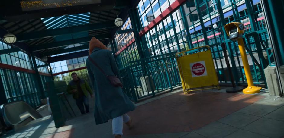 Angela walks to the stairs leading down into the station.