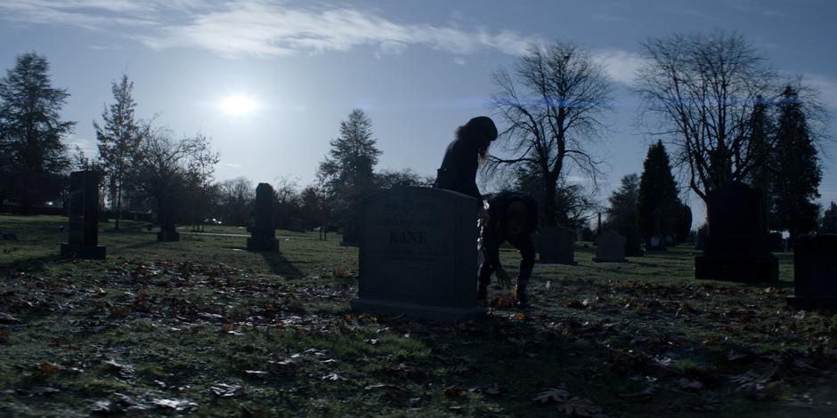 Alice reahces forward as Ocean collapses in front of her gravestone.