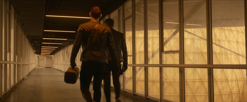 Spock and Pike walk through a hallway to get to the transport point.