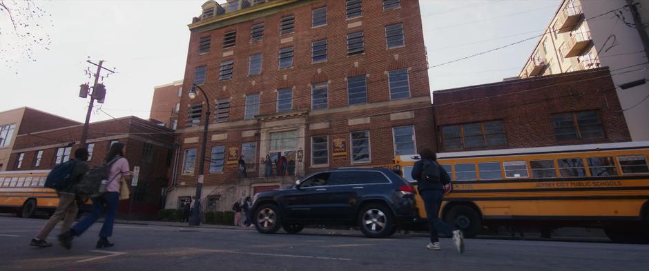 Students cross the street towards the school in the morning.