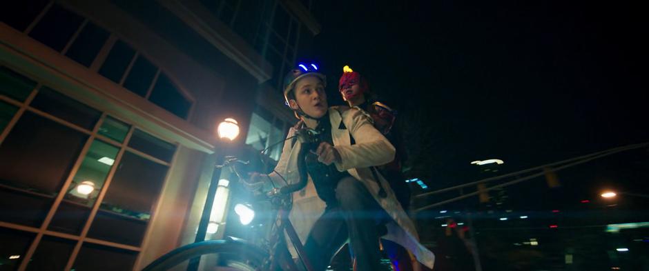 Bruno glances back at Kamala as she rides on the back of his bike after the con.