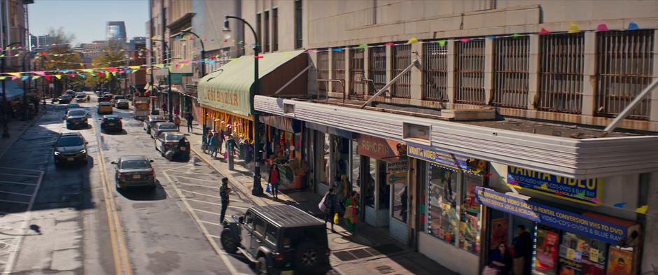 People walk down the sidewalk and visit the various stores.