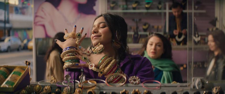 Kamala tries on dozens of pieces of jewelry as her mother approaches from behind her.