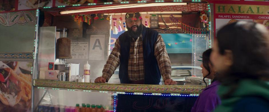 The man running the halal stand greets Kamala and Muneeba.