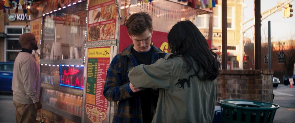 Bruno examines Kamala's bangle while they wait for their food.