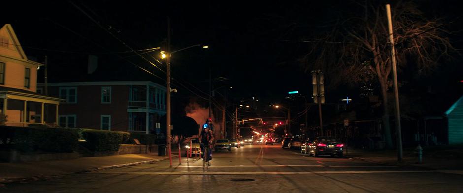 Bruno bikes down the street with Kamala on the back of the bike.