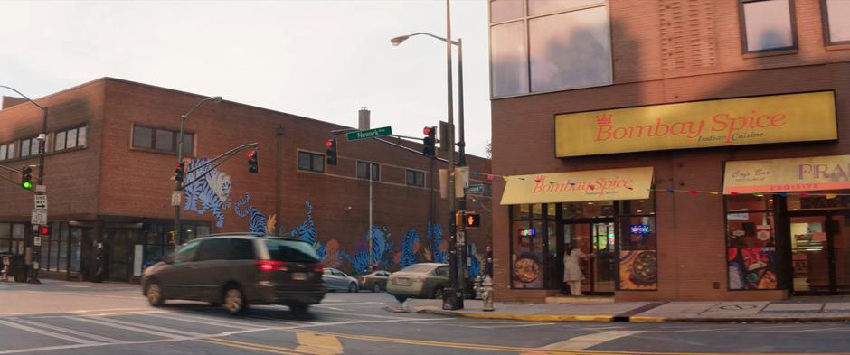 Shot of the exterior of Bombay Spice with a car driving past.