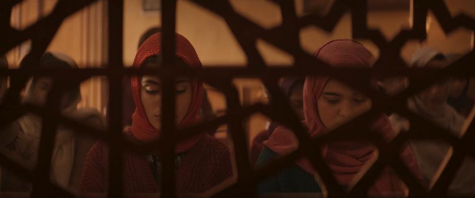 Nakia and Kamala kneel behind the partition as they finish their prayers.