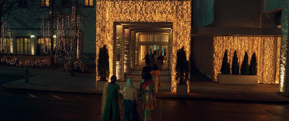 People walk through a arch covered in lights in their way into the wedding.
