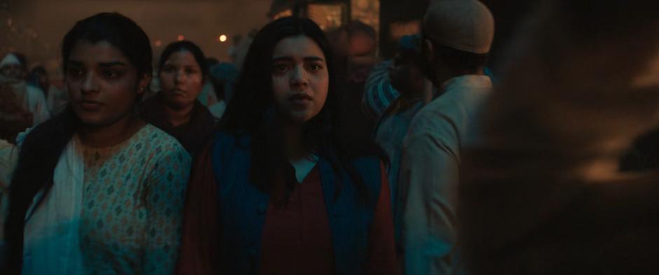 Kamala walks through the crowds along the train platform.