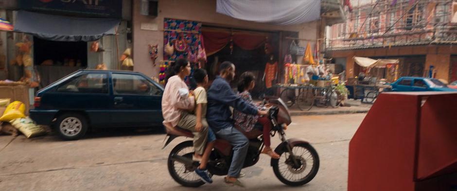 A family sits on motorcycle parked on the side of the road.