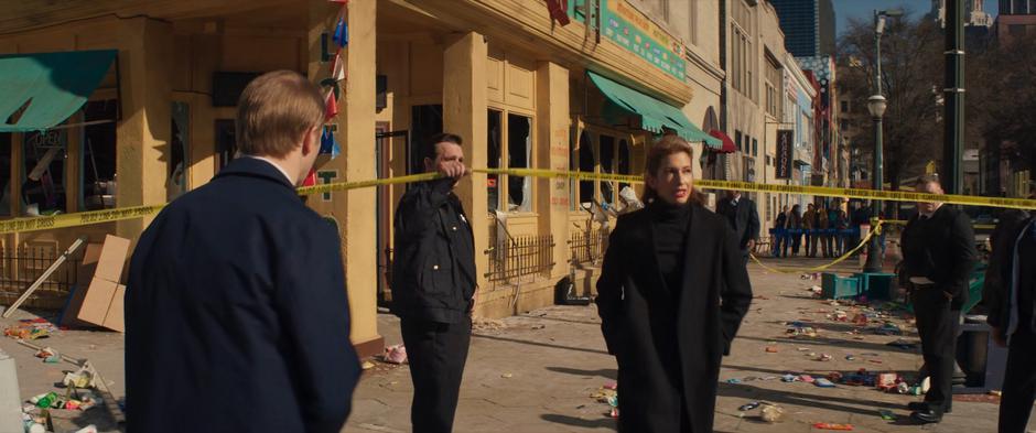 Agent Deever passes under the police tape in front of the ruined store.