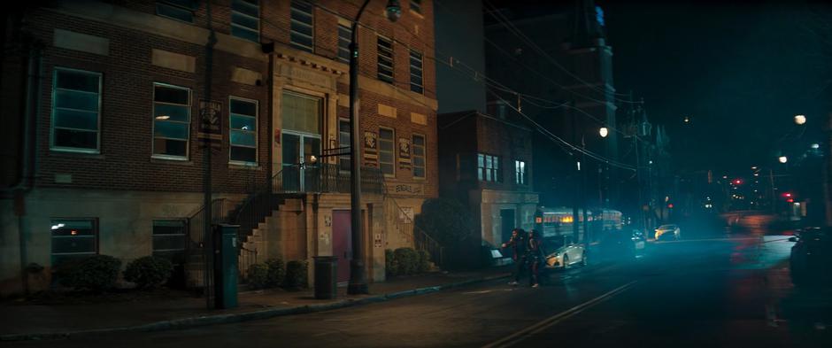 Bruno, Kamran, and Kamala cross the street towards the school at night.