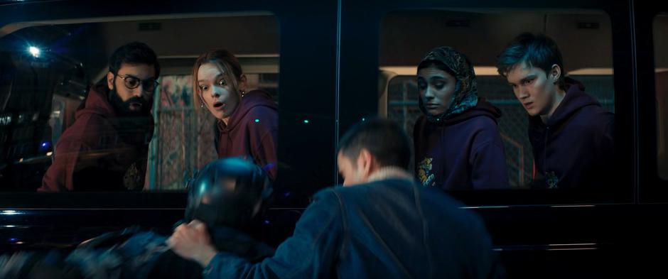 Aamir, Zoe, Nakia, and Bruno watch as Kamran throws a DODC agent against the side of the van where they are being held.