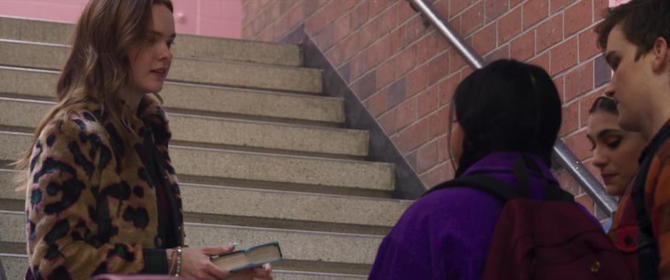 Zoe stops on the stairs after bumping into Kamala and compliments her necklace.