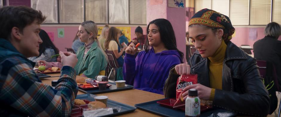 Bruno, Kamala, and Nakia sit at the lunch table and continue their conversation.