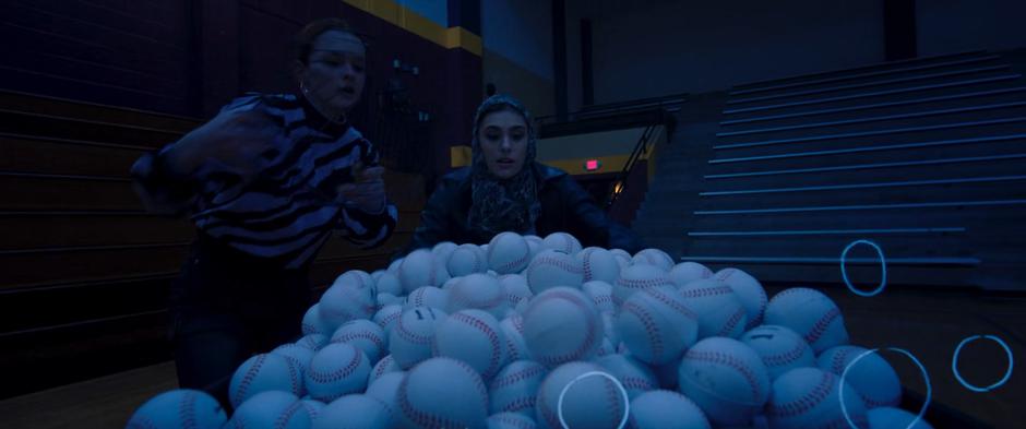 Zoe and Nakia collect softballs in the gym.