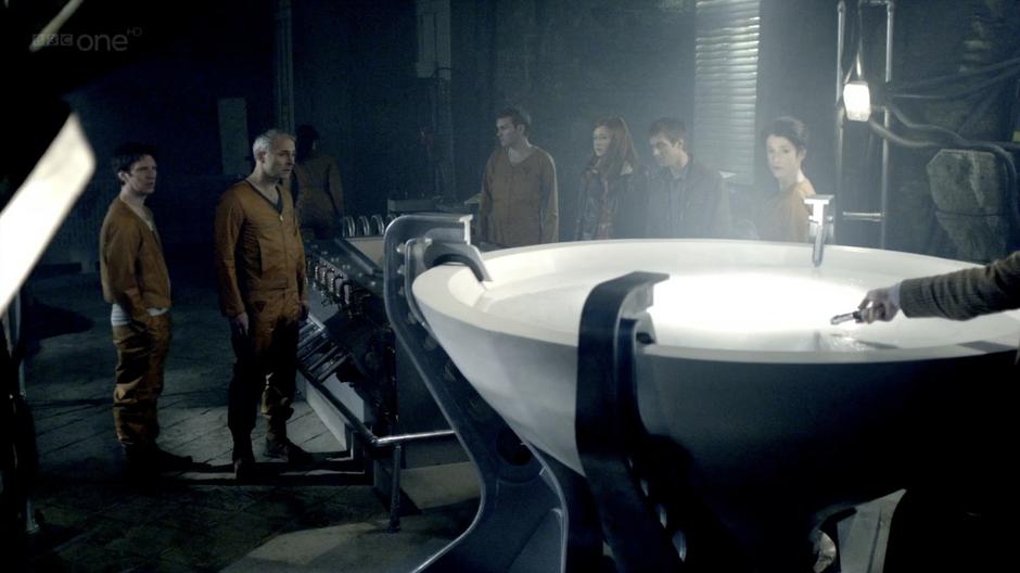 The Monastery crew looks on while the Doctor examines the flesh.