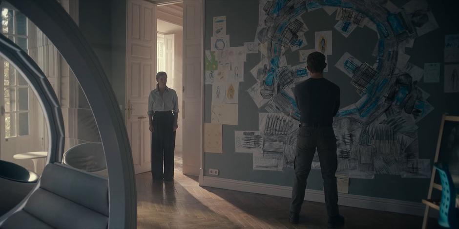 Jillian enters Michael's old room and finds him looking at his drawings on the wall.