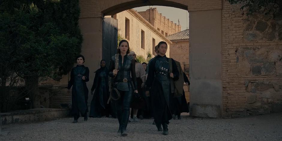 Ava leads Camila, Yasmine, Michael, Bea, and the others through the gate.