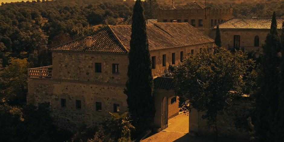 Establishing shot of the front of the villa bathed in orange sunlight.