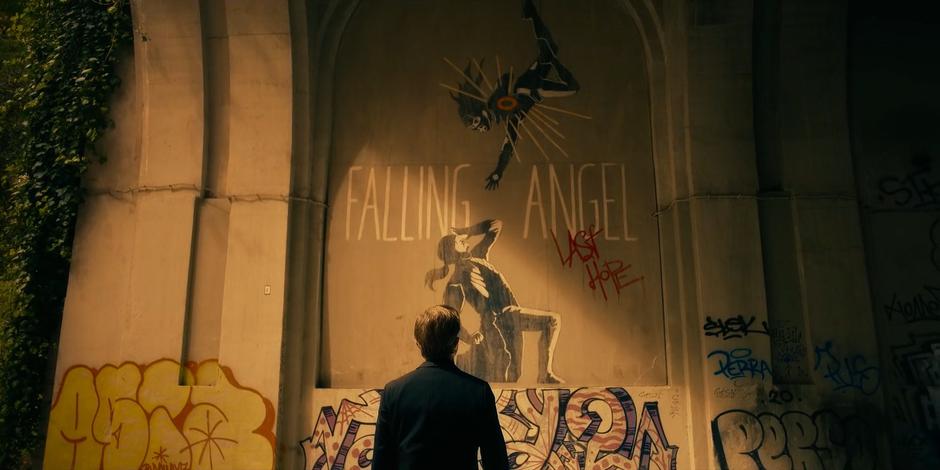 Vincent looks up at the mural depicting Ava as the Falling Angel.