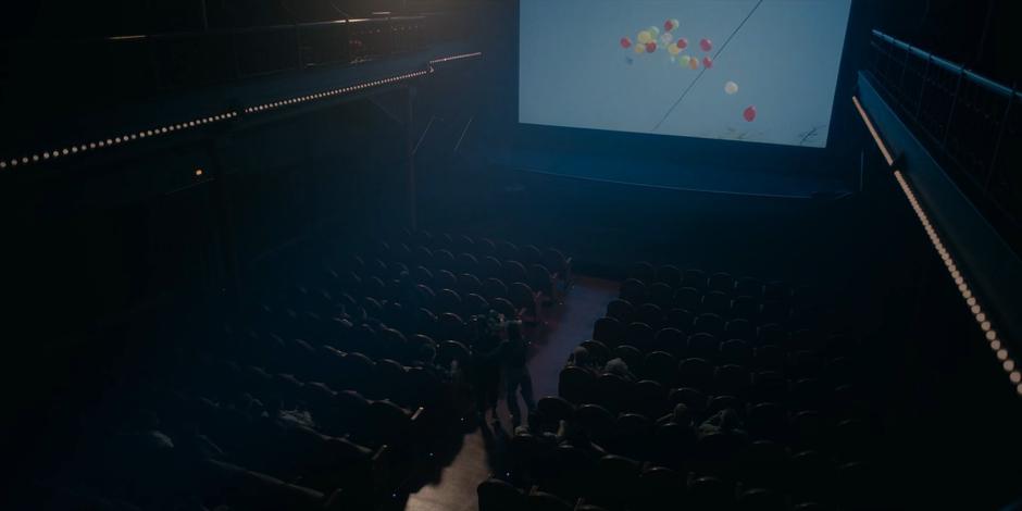 Camila leads Ava and Bea across the cinema as the movie continues playing.