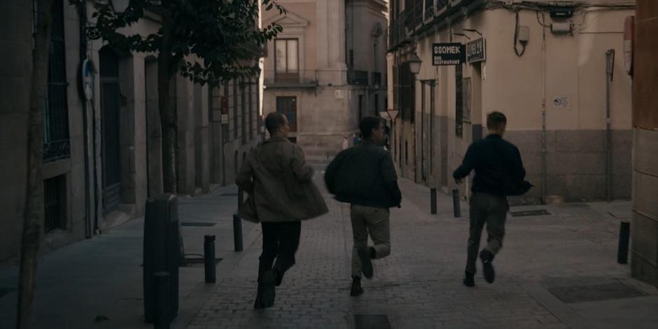 The three goons run around the corner to catch up with Ava and Bea.