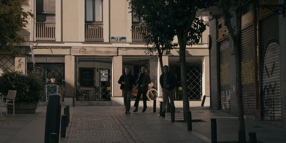 The three goons come around the corner after losing sight of Ava and Bea.