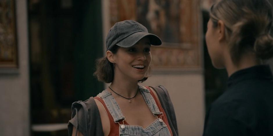 Ava smiles at Bea as they talk on the street.