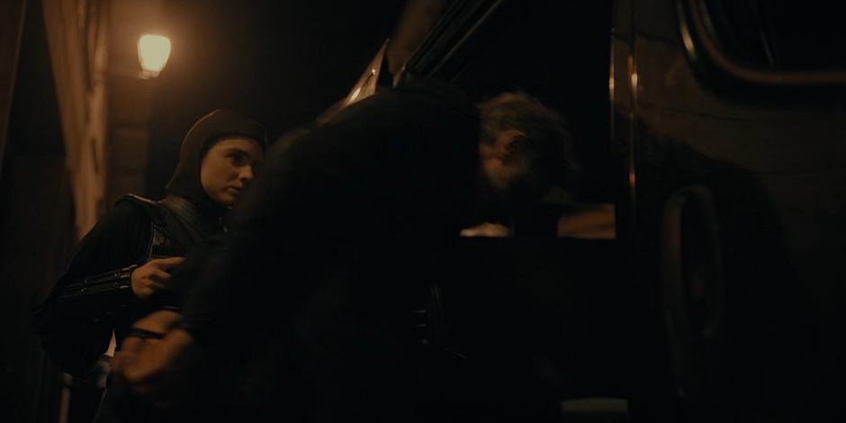 Camila holds on a gun on Vincent as they usher him into the van.