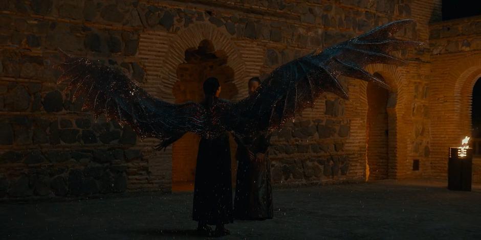 Two wings spread from Lilith's back as she stands in front of Adriel.