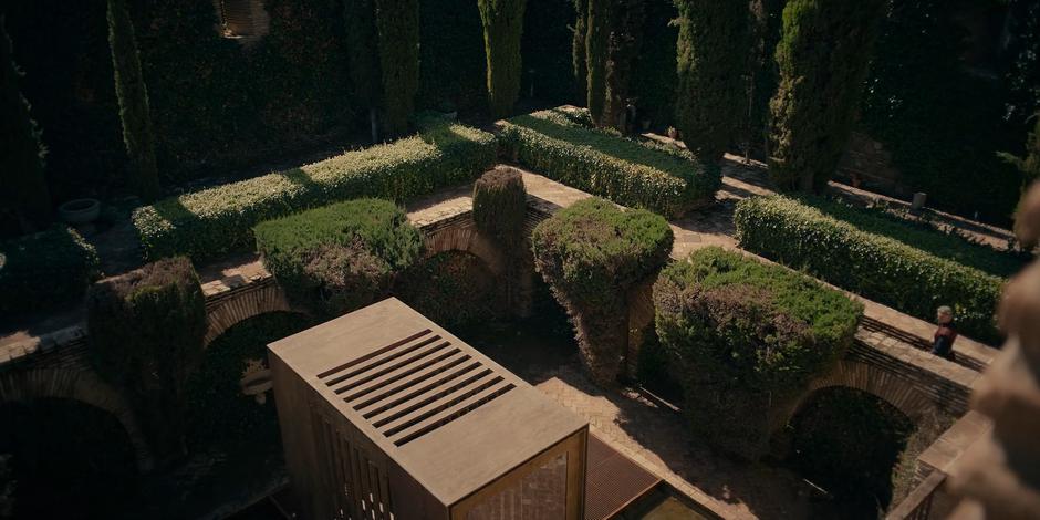 Cardinal Foster walks through the garden carrying Pope Duretti's meal to his cage.