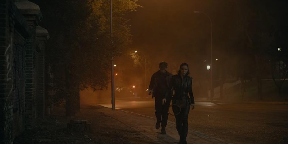 Miguel and Ava walk though the fog after the masked figures.