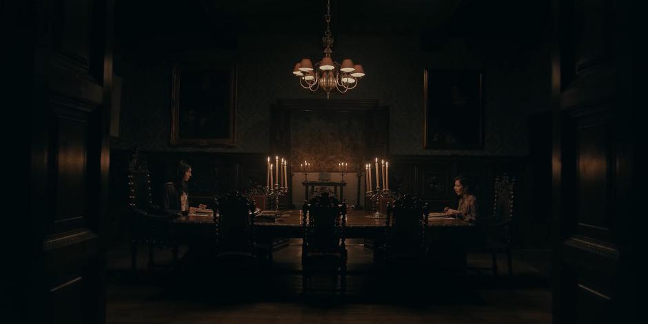 Lilith and her mother sit across from one another at a long table.