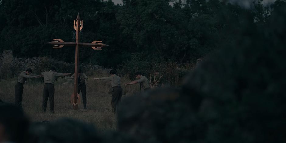 The FBC begin praying around the strange cross in the field.