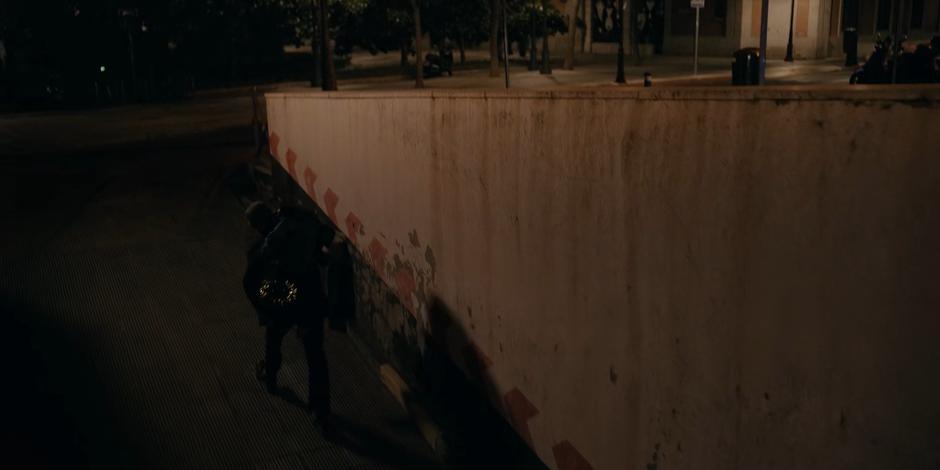 Vincent climbs the ramp from the parkign garage with Ava slung over his shoulder as a cop car races past to the museum.