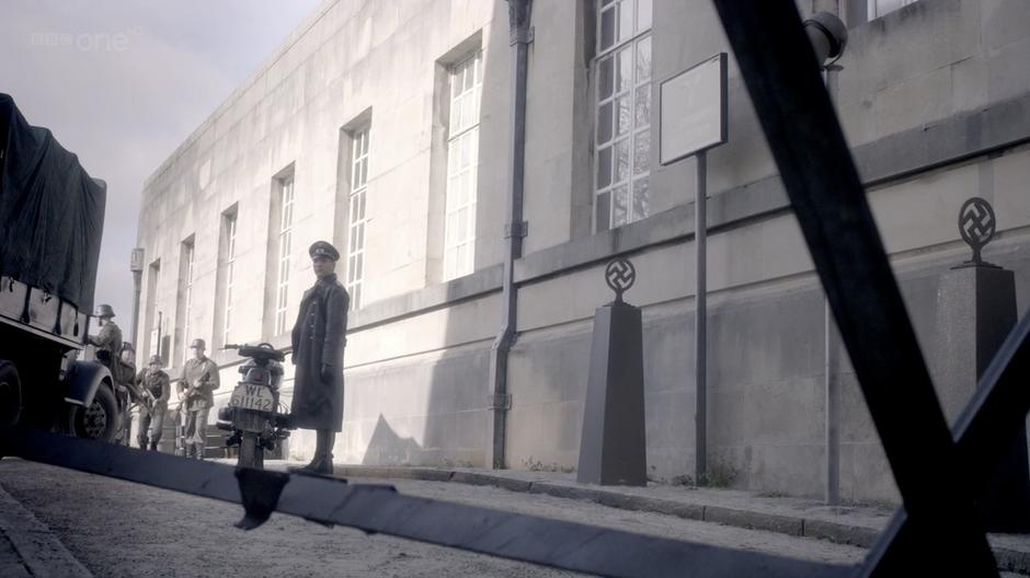 A german soldier sees River coming from the building.