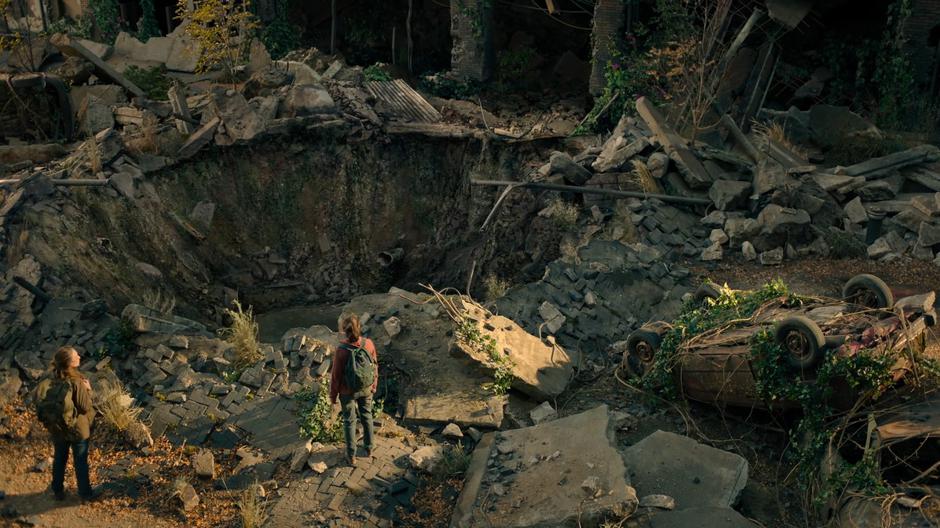 Tess stops when she sees Ellie looking down into the crater.