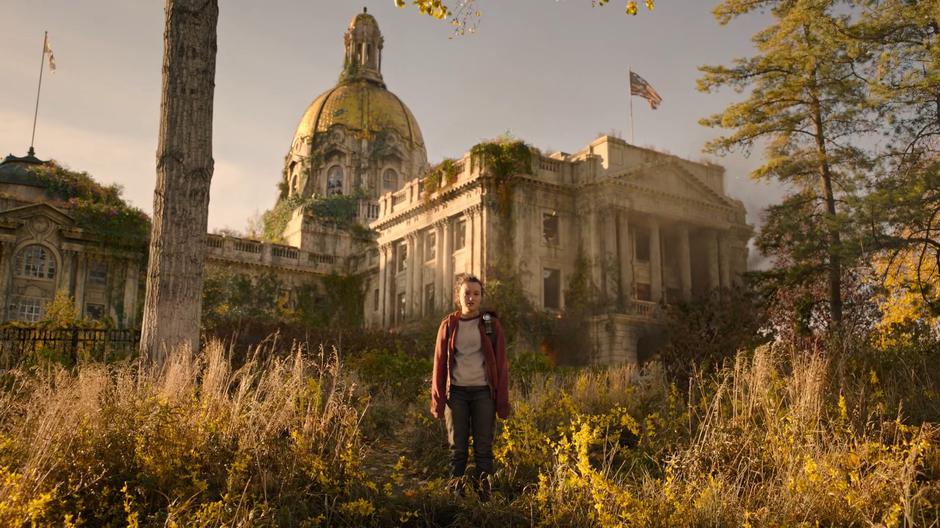 Ellie stands alone in front of the burning building after Joel heads off.