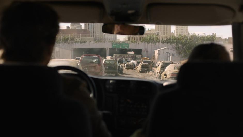 Joel drives the car through the stopped cars outside the tunnel.