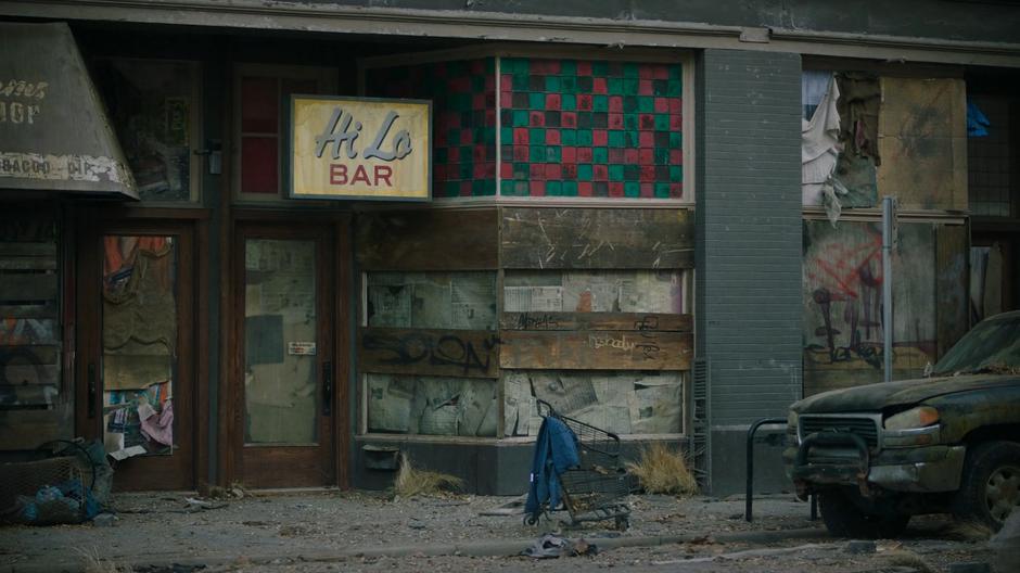 Joel peeks through a small hole in the newspapers covering the inside of the windows of the abandoned bar.