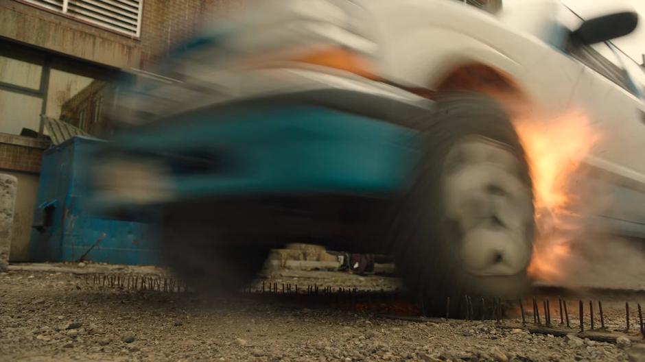 Joel drives the car over a spike strip hidden in the alley.