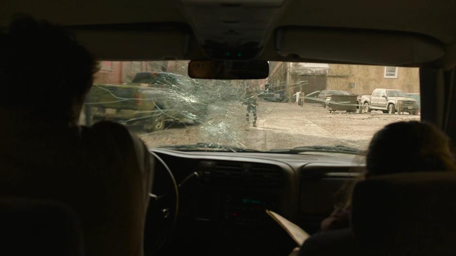 Joel tries to navigate with a broken windshield as someone steps out into the alley.