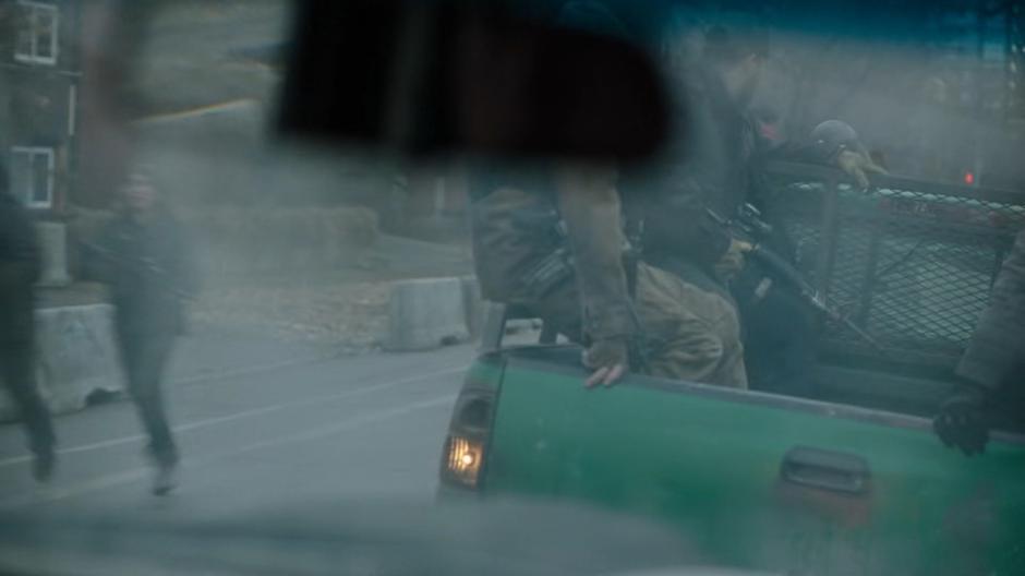 Heavily armed people climb off the back of their trucks into the neighborhood.