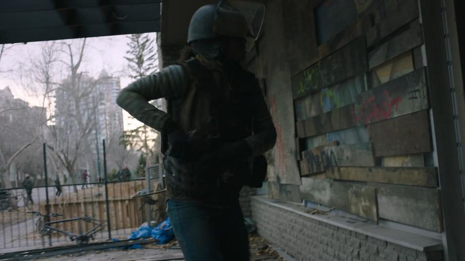 One of the goons pulls her gun after smashing open the door to an apartment building.