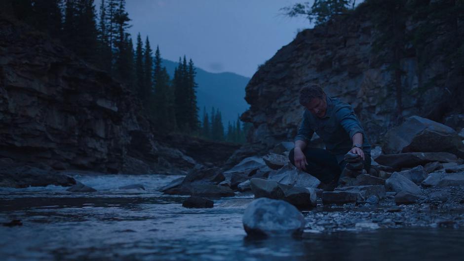 Joel piles a rock onto a cairn he has constructed on the shore.