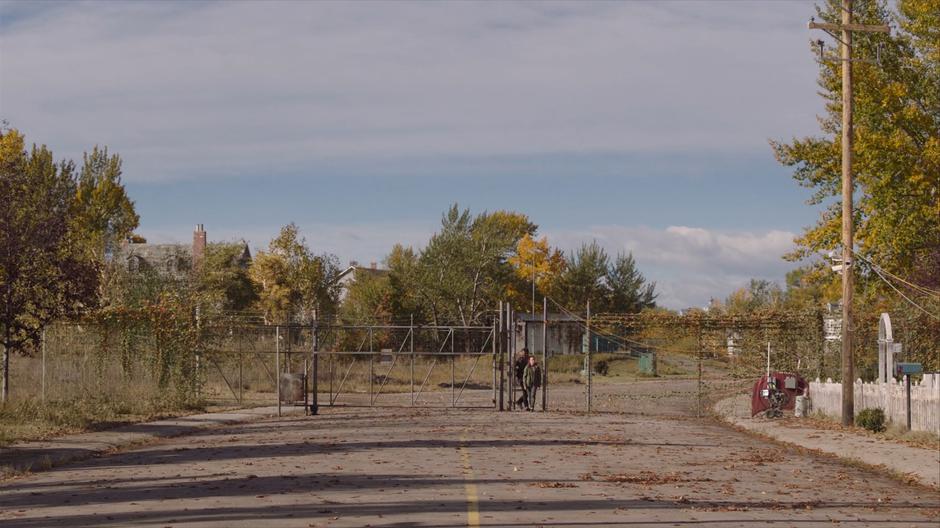 Joel and Ellie pass through the gate into the seemingly deserted neighborhood.