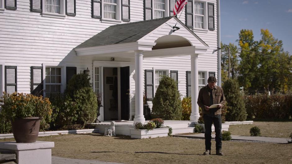 Joel stands on the front lawn reading Bill's letter.