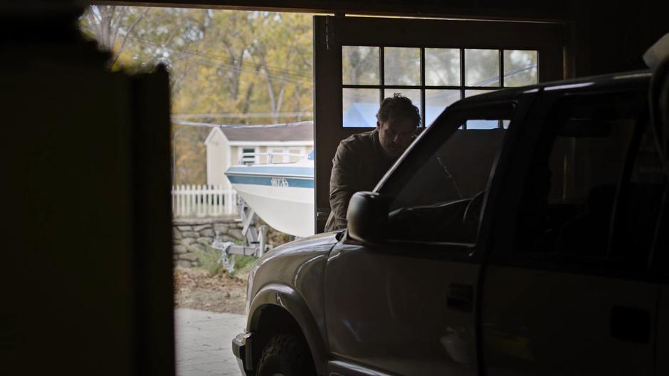 Joel leans on the hood of the car Bill left for him.